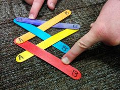 a child's hand pointing at the letters made out of colored sticks