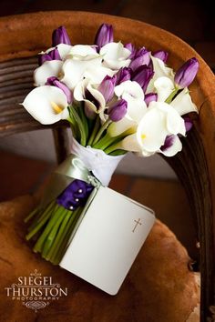 a bouquet of purple and white flowers sitting on top of a wooden chair next to a notepad