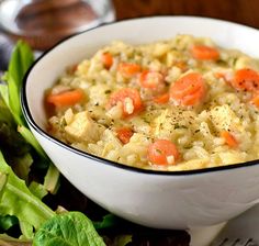 a white bowl filled with rice and carrots on top of a plate next to lettuce