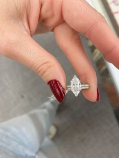 a woman's hand with a ring on it and a red manicured nail