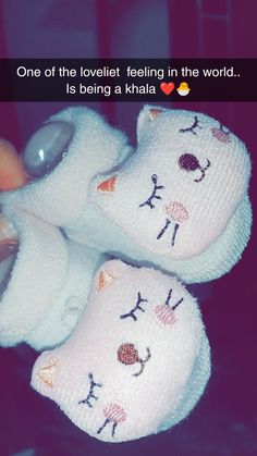 someone is holding two pairs of baby slippers with the words, one of the lovely feeling in the world is being a khlia