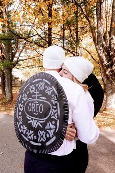 two people in white hats hugging each other and holding an oreo cookie on the road