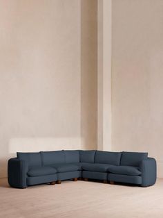 a large blue sectional sofa sitting on top of a wooden floor next to a white wall