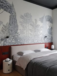 a bed sitting under a window next to a wall with trees painted on the walls