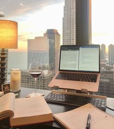 an open laptop computer sitting on top of a desk next to a glass of wine