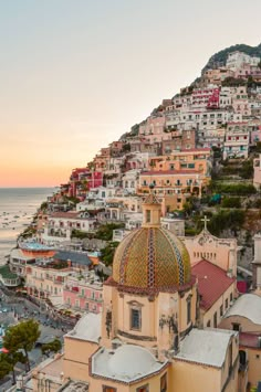 an aerial view of a city with buildings on the hillside and ocean in the background