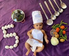 a baby wearing a chef's outfit sitting next to various cooking utensils