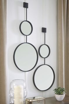 two circular mirrors hanging on the wall next to a candle