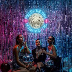 three women sitting in front of a disco ball