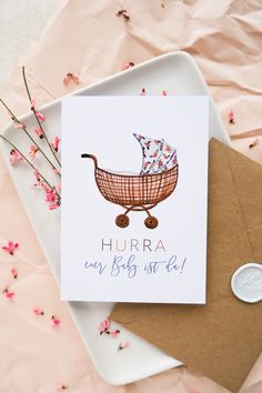 a card with a baby stroller on it next to pink flowers and a penny