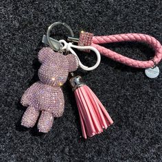 a pink keychain with a teddy bear charm attached to it's side