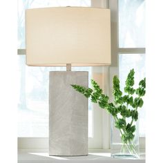 a table lamp next to a vase with a plant in it on a window sill