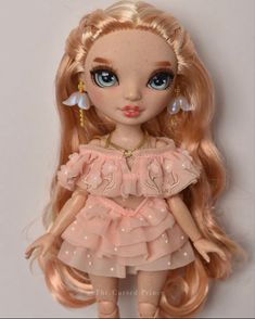 a doll with long blonde hair and blue eyes wearing a pink frocked dress