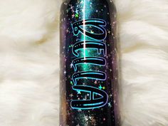 a water bottle with the word glitter on it sitting on a white fur covered surface