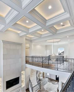 a large living room with white walls and wood flooring on the second floor, along with a staircase leading to an upper level balcony