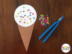 an ice cream cone with sprinkles and scissors next to it on a table