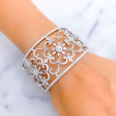 This exquisite 18k white gold bangle bracelet, weighing 63.1 grams, features an extravagant floral motif adorned with dazzling diamonds. The white gold finish enhances its luxurious appeal, making it perfect for any special occasion. The bangle is set with 8.43 carats of F-G color, VS quality diamonds in round and marquise shapes. With an oval opening of 2.4 inches, this cuff bangle with side hinges offers both elegance and comfort. Ideal for those who appreciate high-quality craftsmanship and t Luxury Diamond Accented Bangle For Party, Luxury Brilliant Cut Cuff Bracelet For Wedding, Elegant Diamond Cut Cuff Bracelet For Anniversary, Luxury Bangle With Diamond Accents For Party, Luxury Wedding Cuff Bracelet With Brilliant Cut, Glamorous Diamond Bracelet With Accents For Formal Events, Glamorous Diamond Bracelet For Wedding, Glamorous Diamond Wedding Bracelet, Glamorous Formal Diamond Bracelet With Accents