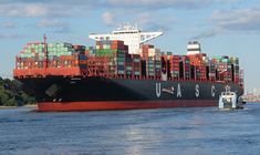 a large cargo ship with lots of containers on it's side in the water