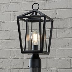 an outdoor light on a post with brick wall in the background and white bricks behind it