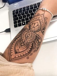 a woman's arm with a tattoo on it and a laptop in the background