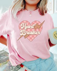 PLEASE NOTE, DUE TO THE BUSY HOLIDAY SEASON ANY ORDERS PLACED AFTER 12/09/24 ARE NOT GUARANTEED TO ARRIVE BY CHRISTMAS.Looking for a comfortable and stylish shirt to wear on Valentine's Day? Look no further than the Comfort Colors Heart Breaker Valentine shirt! This shirt is made from soft, breathable fabric that will make you feel comfortable all day long. It also features a retro style Heart Breaker saying on it. Perfect as a gift for your girlfriend or yourself, the Valentine's Day Comfort Co Trendy Heart Graphic Tops For Loungewear, Trendy Loungewear Tops With Heart Graphic, Casual Pink T-shirt With Heart Print, Trendy Heart Print Tops For Loungewear, Casual Heart Graphic Top For Loungewear, Heart Graphic Relaxed Fit Top For Loungewear, Relaxed Fit Heart Graphic Top For Loungewear, Relaxed Fit Loungewear Tops With Heart Graphic, Casual Heart Print Shirt For Spring