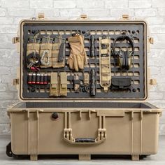 an outdoor tool box with tools and equipment in it on the floor next to a brick wall