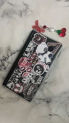 a cell phone case with stickers on it sitting on a marble surface next to a keychain