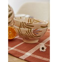 two bowls sitting on top of a table next to an orange slice