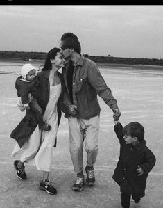 a black and white photo of a man, woman and two children walking on an airport tarmac