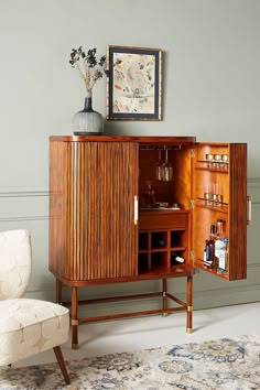 a room with a chair, cabinet and vase on the floor next to a painting