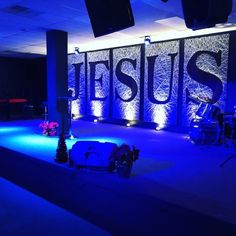 a stage set up with blue lights and flowers on the floor for a worship service