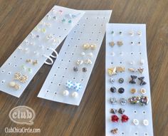 several pairs of earrings are sitting on a table next to some white pegboards with holes in them