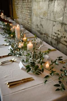 a long table with candles and greenery on it