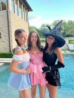 three girls in costumes standing next to a pool