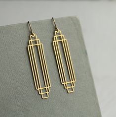 These great earrings are made with solid brass and feature a graduated art deco design.  They remind us of classic Deco architecture, like the Chrysler building!   The earrings measure 45mm (just under two inches) in length and have gold plated ear wires.   They have been designed and made in our Edinburgh studio.   This piece of handmade jewellery comes packaged in a nice recycled gift box with a handmade tag, all ready to give or keep. We also have these earrings in silver, as well as  many other Art Deco designs!  🖤 FASTER SHIPPING 🖤 Need this fast? We offer a Faster Shipping option here: https://www.etsy.com/uk/listing/100107311/faster-shipping-priority-post-upgrade 🖤 GIFT MESSAGE & WRAP SERVICE! 🖤 https://www.etsy.com/uk/listing/750160511/gift-wrap-wrapping-personalised-card?ref=l Art Deco Jewelry Rings, Art Deco Inspired Jewelry, Cement Jewelry, Art Deco Jewellery Design, Gold Art Deco Earrings, Art Deco Jewellery, Bijoux Art Deco, Silk Purse, Minimalist Earrings Gold