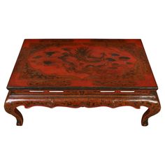 a wooden coffee table with red paint on the top and brown wood trimmings