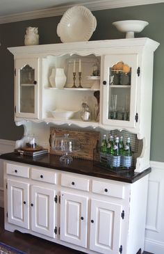 a kitchen with white cabinets and black counter tops in the center, along with wine glasses on top