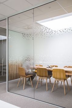 an office meeting room with glass walls and wooden chairs