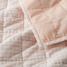 an unmade bed with pink and white checkered sheets