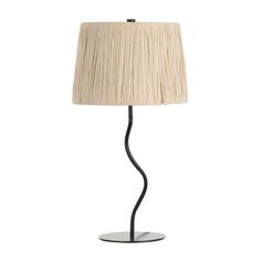 a lamp that is on top of a white surface with a black base and a beige shade