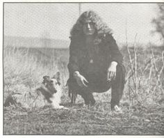 an old black and white photo of a woman sitting in the grass with her dog