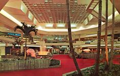 the interior of a shopping mall with palm trees and red carpeted flooring on both sides