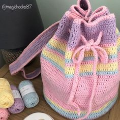 a crocheted bag sitting on top of a wooden table next to some yarn