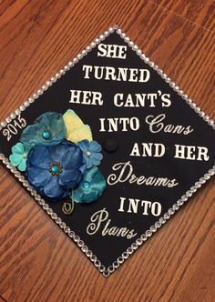 a graduation cap decorated with flowers and writing on the front is sitting on a wooden table