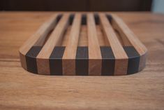 a wooden cutting board sitting on top of a table with black and brown strips around it