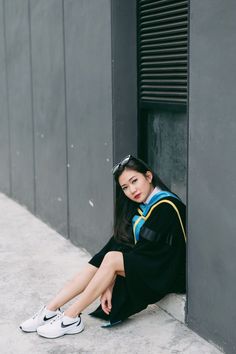 a young woman sitting on the ground next to a building