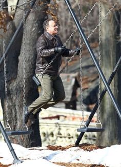 a man walking across a rope bridge with the caption, please enjoy this photo of tom hanks on a swing