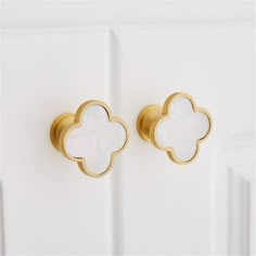 a pair of white and gold door knobs on a white door with a flower design