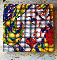 a large piece of art made out of legos on a brick wall, with the image of a woman's face