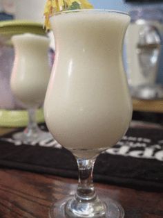 two glasses filled with white liquid sitting on top of a wooden table next to each other